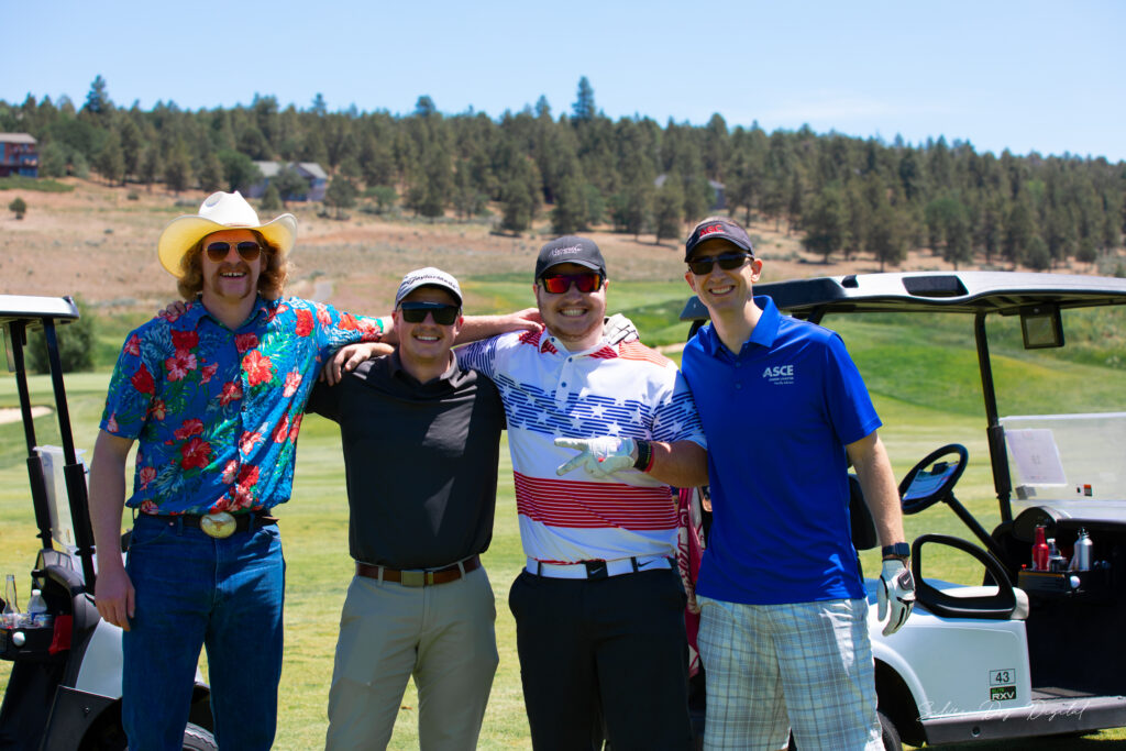 four men posing next to golf cart