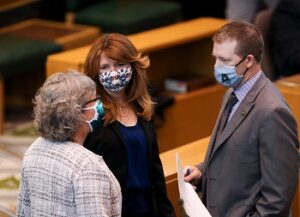 two women and a man wearing masks