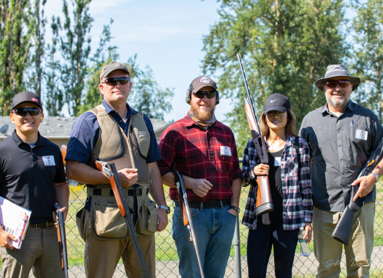 four men and woman holding guns at shooting event