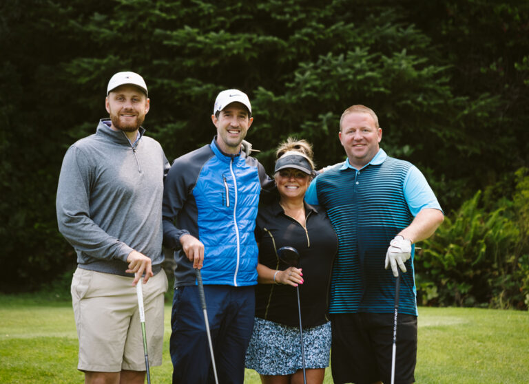 four smiling golfers