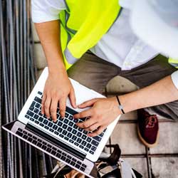 man in safety vest on laptop