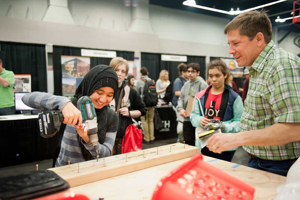 man showing young girl to use drill