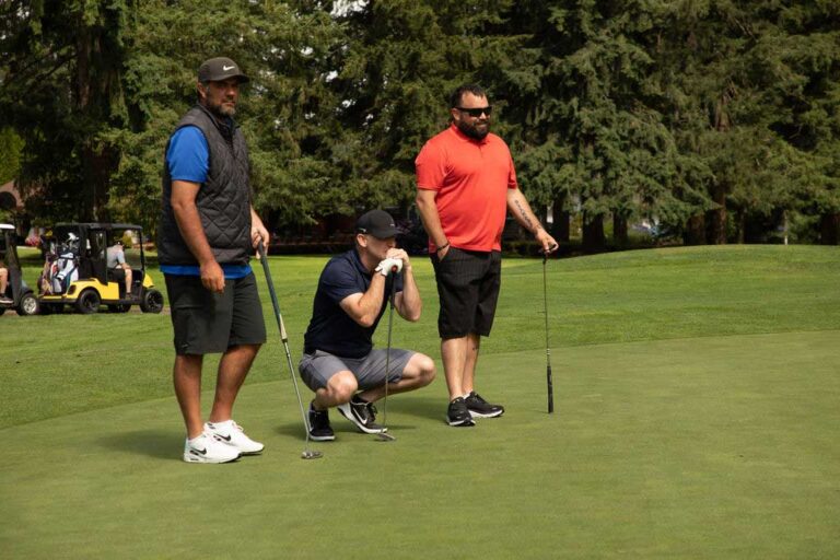 three golfers assessing a putt