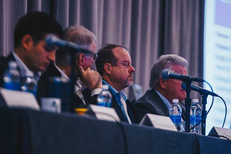 men sitting at a table with microphones