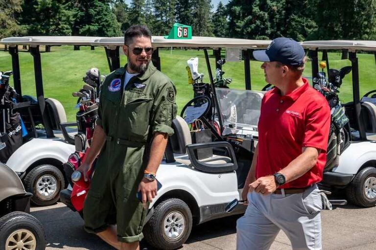 two men standing in front of golf carts