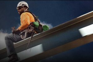 man sitting on beam wearing safety equipment