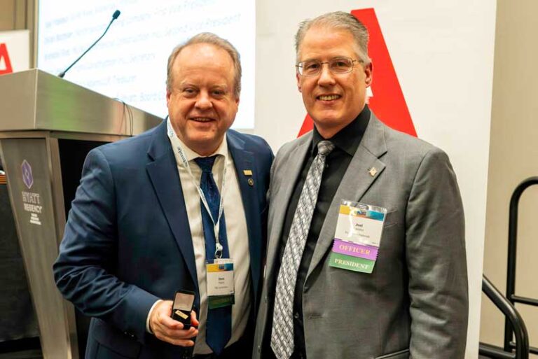 two men wearing ties, one holding a gavel