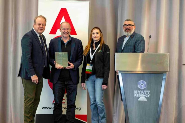 four people one holding an award