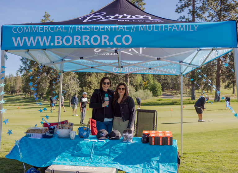 two ladies at a sponsor table under a canopy