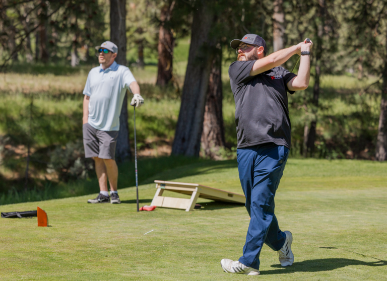 one man hitting a golf ball and a man watching