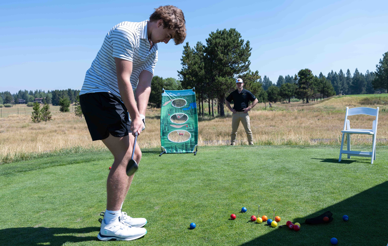 young man putting with multicolored golf balls