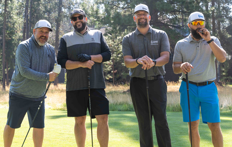 four men standing with golf clubs