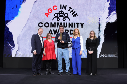 five smiling people with an award
