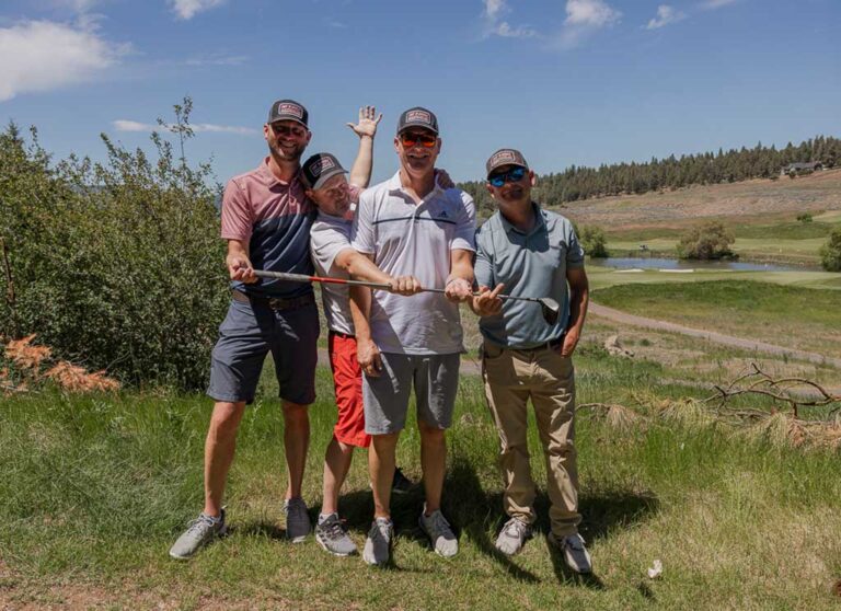 three men and one woman golfer smiling for camera