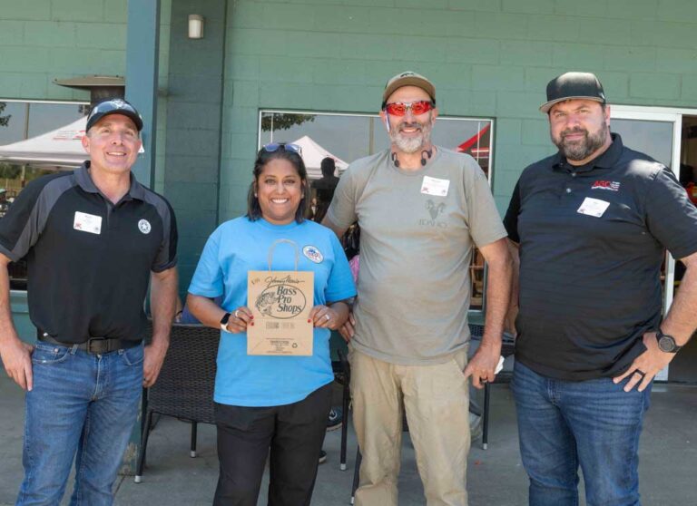 three men and a woman smiling and holding an award