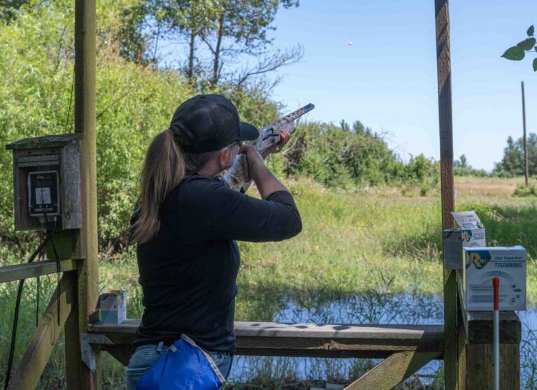 woman wearing a hat shooting a rifle