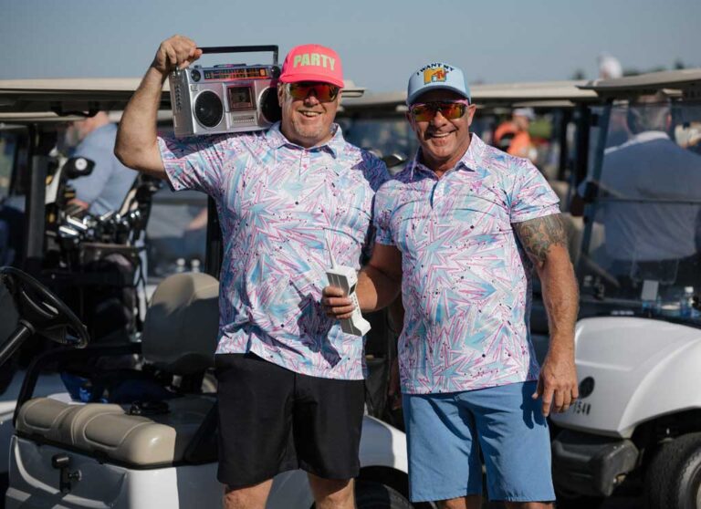 two smiling men in crazy golf shirts, one flexing muscles