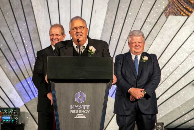 three smiling men at podium