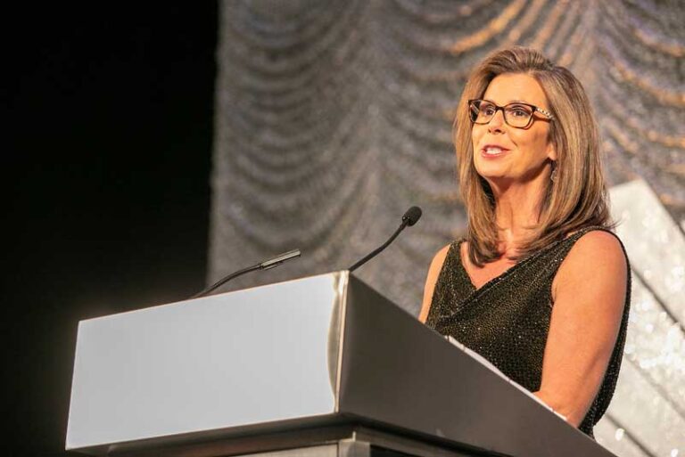 woman with glasses speaking at podium