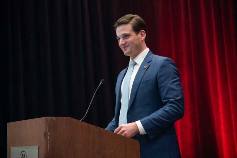 smiling man in suit at podium
