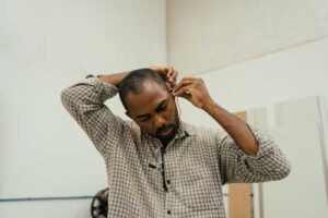 man pulling his ear to insert ear plg