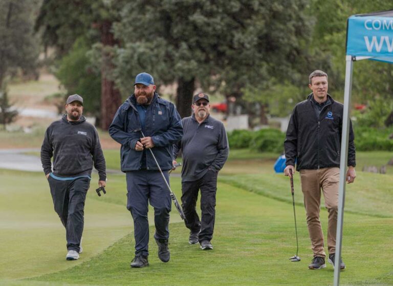 four male golfers walking on the course