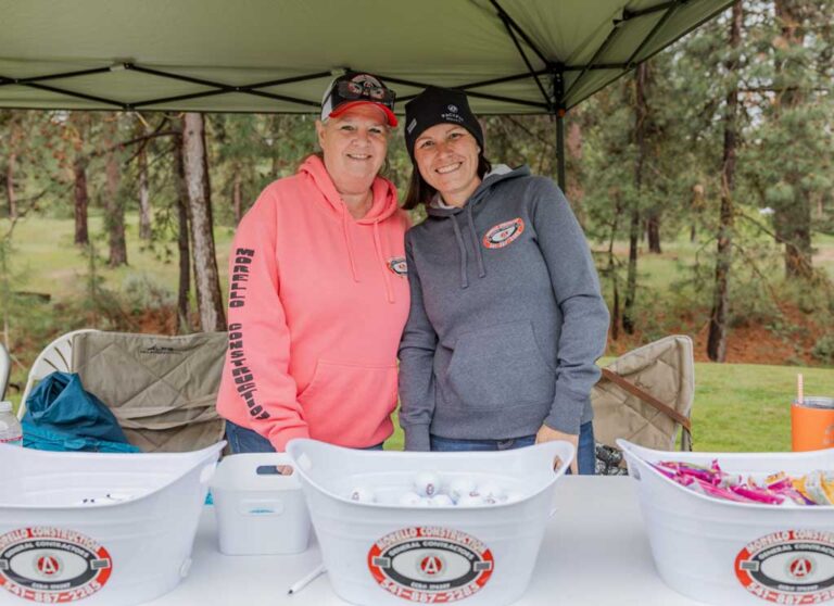 two smiling women at a sponsor table