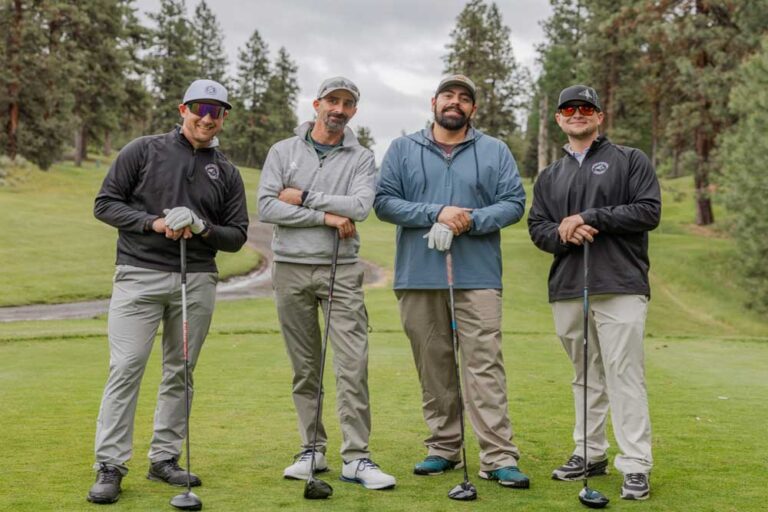 four players leaning on golf clubs