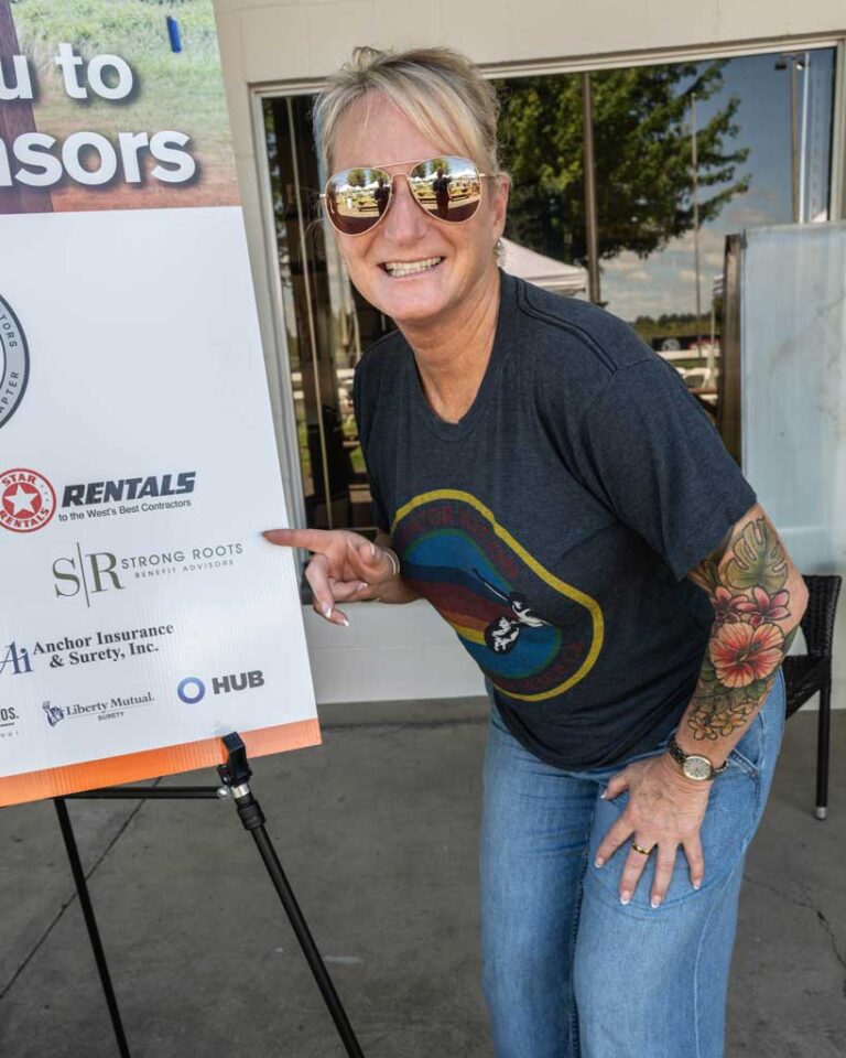 woman with tattoo wearing sunglasses pointing at a sign