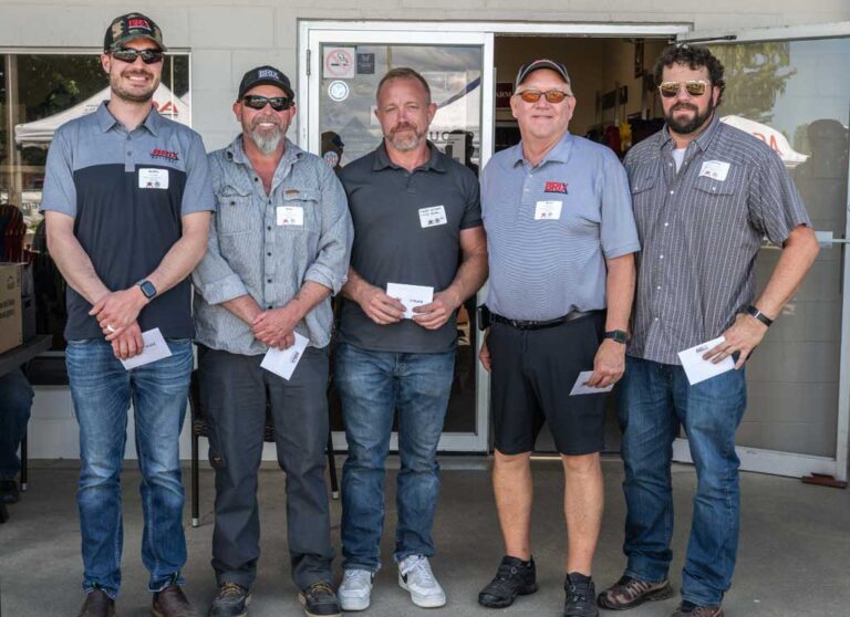 four men smiling, holding checks