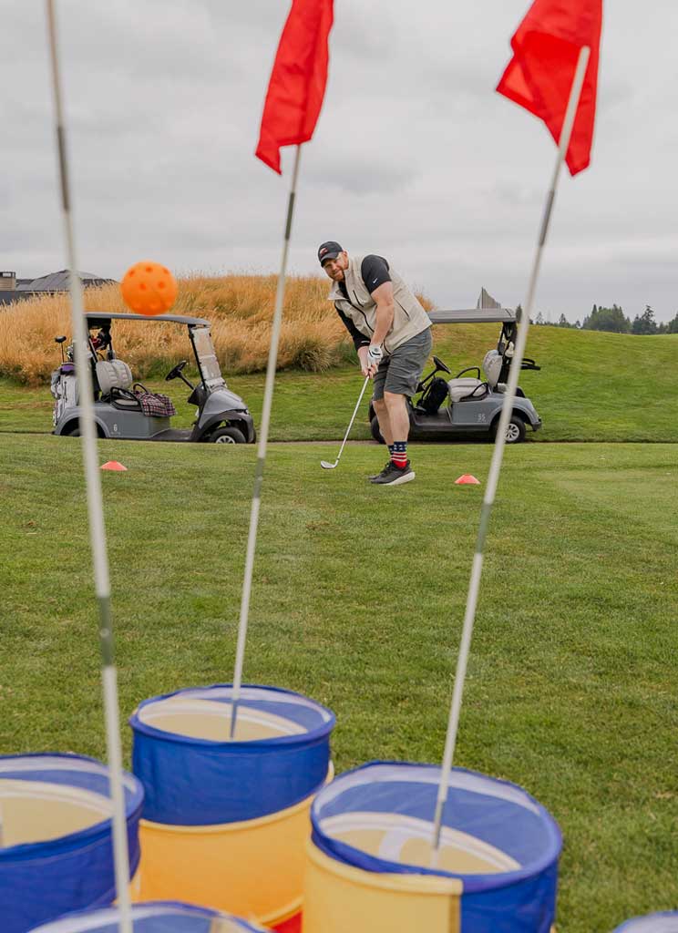 a man putting a golf ball towards some flags