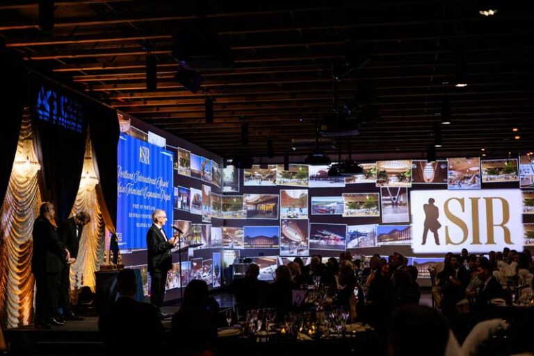 a man at a podium with a background of photos