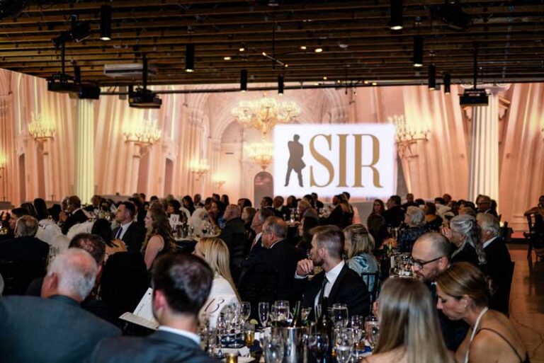 a crowd at a gala with a stage in the background